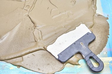 Spatula yüzeydeki çimento harcının üzerinde duruyor.