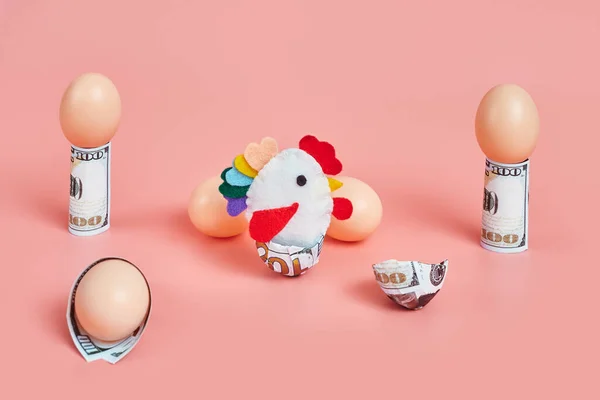 toy chicken and eggshells with 100 dollar bills. concept. pink background