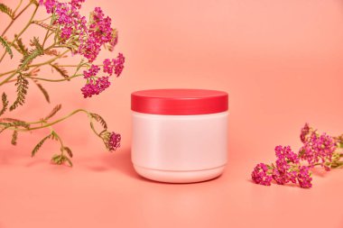 Üzerinde yazı olmayan pembe bir kavanoz. Kırmızı çiçek kabuğunun arka planında. konsept kozmetik cilt bakımı