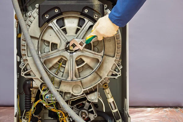 master repairs washing machine. repair of equipment with wrench