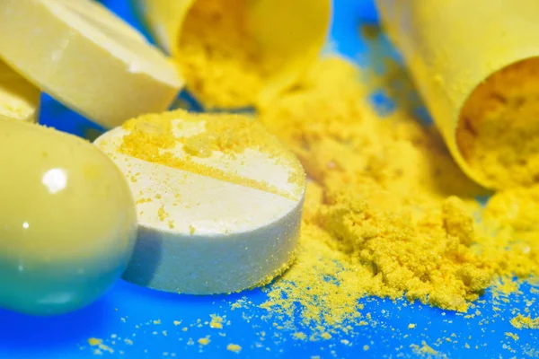 broken yellow pill and capsules close-up. macro. blue background