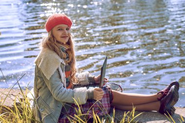 Sonbaharda genç bir kız ve nehir kenarında defterleri var.