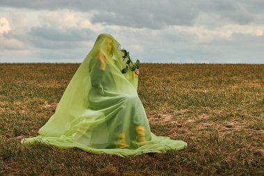 Elinde beyaz gülle koltukta oturan bir kadın. Çarşaflı bir kadın.