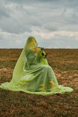 Elinde beyaz gülle koltukta oturan bir kadın. Çarşaflı bir kadın.