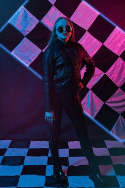 Yarış gözlüklü, deri ceketli neon ışıklı kızın portresi bitiş bayrağının arka planında