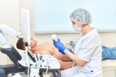 Doktor kadın ve hasta adam hastanede ultrason cihazları üzerinde çalışıyor.