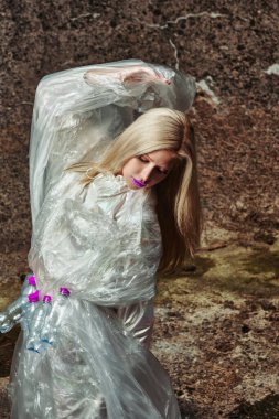 Moda yaratıcı. Plastik şişelerle selofanda poz veren bir model. konsept