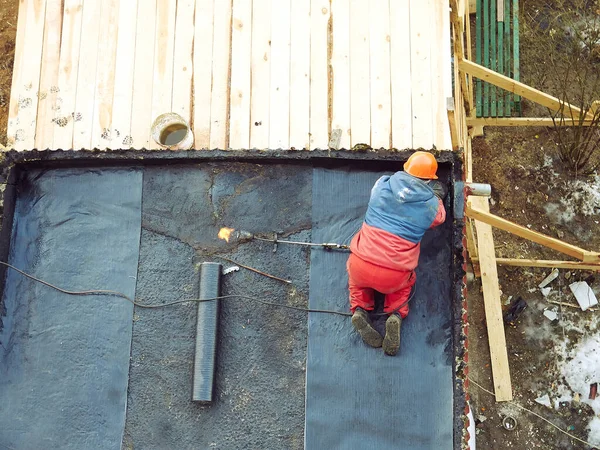 worker repairs the roof. laying roofing material