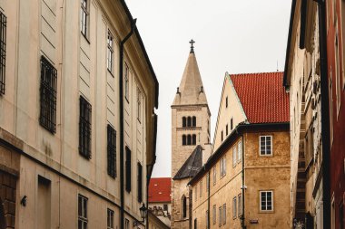 Dar sokakları olan eski bir kasaba. Taş duvarlar, kırmızı çatılar. Eski tapınağın yüksek çan kulesi çatılar arasında görünür..