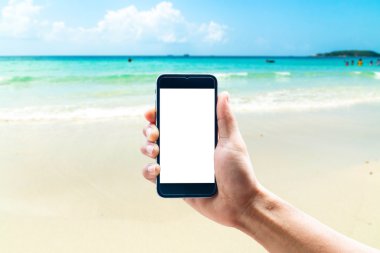 Dikey konumda smartphone telefon kullanarak el, deniz arka plan bulanıklık.