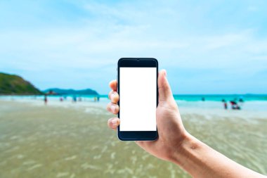 Dikey konumda smartphone telefon kullanarak el, deniz arka plan bulanıklık.