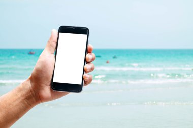 Dikey konumda smartphone telefon kullanarak el, deniz arka plan bulanıklık.