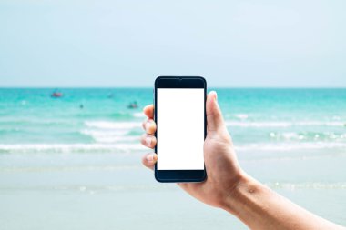 Dikey konumda smartphone telefon kullanarak el, deniz arka plan bulanıklık.