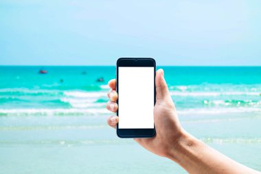 Dikey konumda smartphone telefon kullanarak el, deniz arka plan bulanıklık.