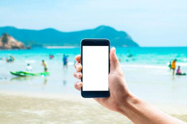 Dikey konumda smartphone telefon kullanarak el, deniz arka plan bulanıklık.