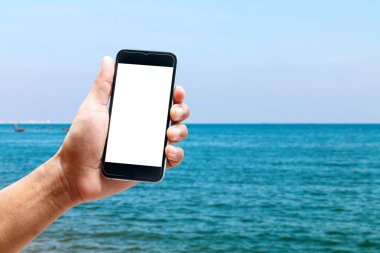 Dikey konumda smartphone telefon kullanarak el, deniz arka plan bulanıklık.