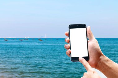 Dikey konumda smartphone telefon kullanarak el, deniz arka plan bulanıklık.