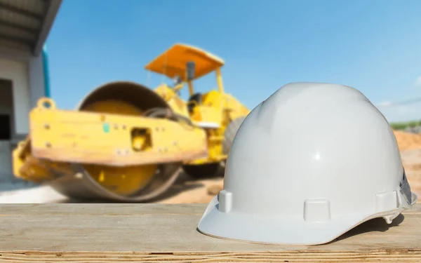 Ingeniería de seguridad y un casco que descansa en los detalles de la obra con una excavadora — Foto de Stock