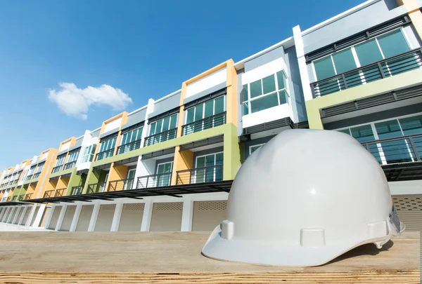 Casco di sicurezza e impianto architetto su tavolo in legno con costruzione di edifici — Foto Stock