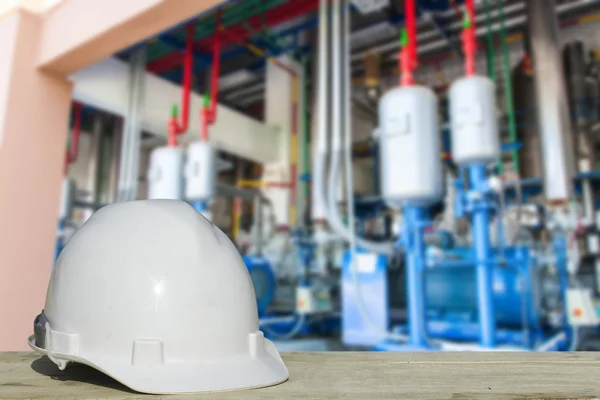 Engenharia de segurança e um capacete descansando sobre os detalhes dos compressores de refrigeração . — Fotografia de Stock