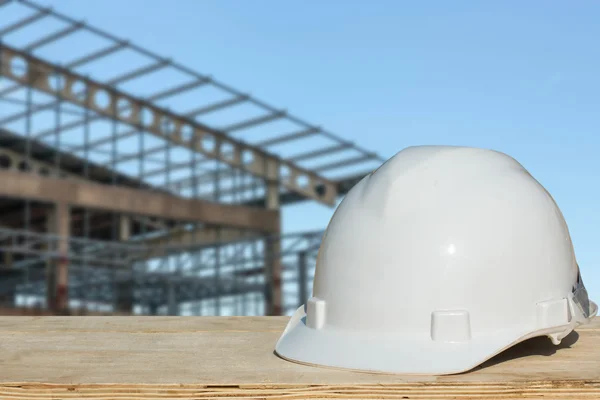 Безпечний шолом і архітектурний завод на дерев'яному столі з будівництвом — стокове фото