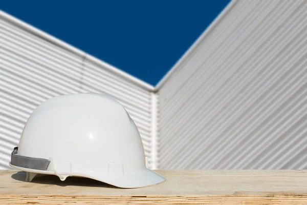 Casque de sécurité et usine d'architecte sur table en bois avec construction de bâtiments — Photo