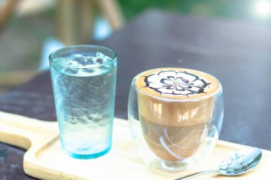 Bir fincan sıcak latte sanat cappuccino Masada sıcak kahve fincanı, Tim taze demlenmiş kahve Yüzeyde güzel latte sanat ile.