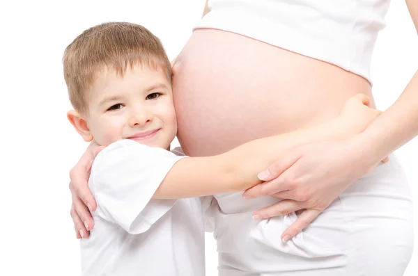 Leuke jongen knuffelen buik zwangere moeder — Stockfoto