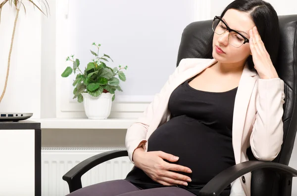 疲惫的怀孕女子，坐在办公室里的工作场所 — 图库照片