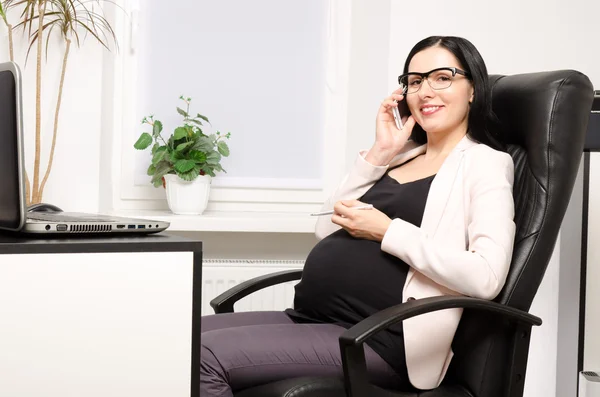 Donna incinta che parla al telefono in ufficio — Foto Stock