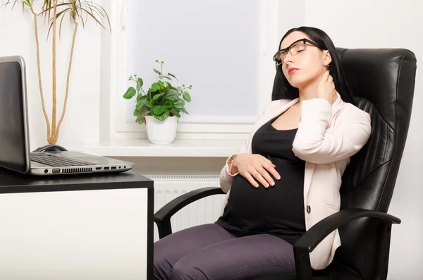 Mujer embarazada cansada sentada en el lugar de trabajo —  Fotos de Stock