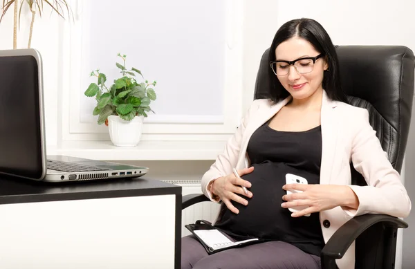 Beautiful pregnant woman at the workplace Stock Picture