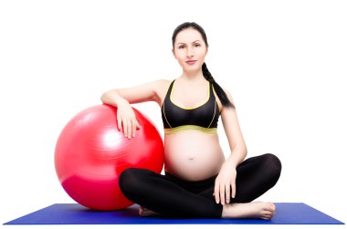 Yoga mat fitball ile oturan genç, güzel bir hamile kadın portresi