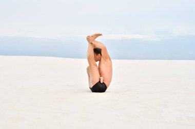 Genç adam plajda spor yapıyor.