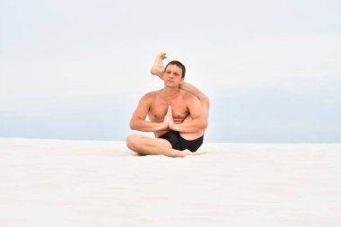 Genç adam sahilde ayaklarının arkasında oturuyor.