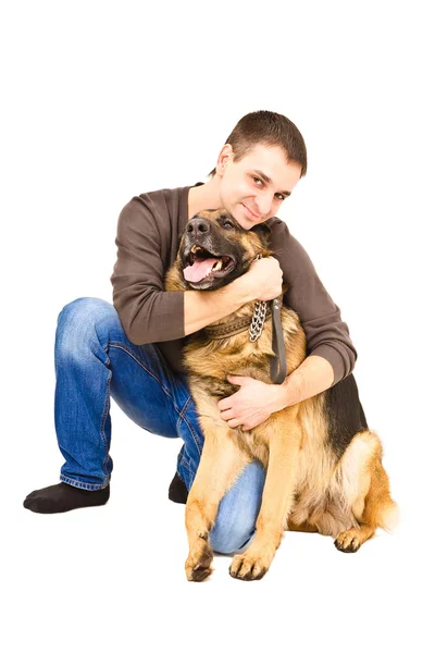 Glücklicher junger Mann umarmt einen deutschen Schäferhund — Stockfoto