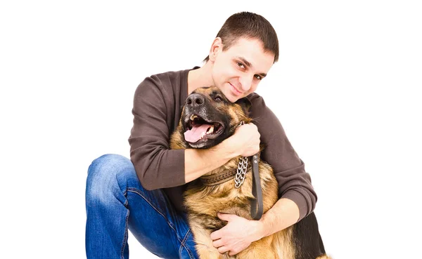 Glücklicher junger Mann umarmt einen deutschen Schäferhund — Stockfoto