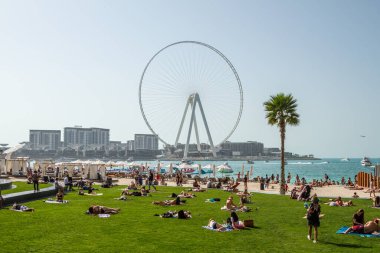 Dubai, BAE. Dubai Marina Jumeirah plajı. İnsanlar çimlerin ve kumların üzerinde. Dubai inşaatı