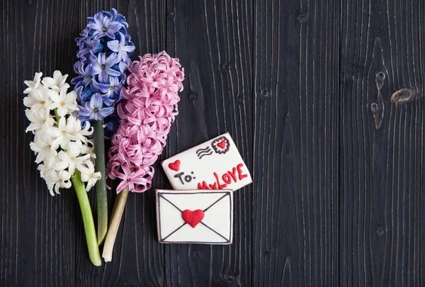 Dark background with hyacinths and biscuits in the form of letters — Stock Photo, Image