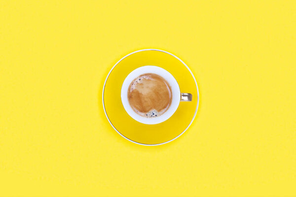 Flat lay of cup of coffee on yellow background with copy space. Concept morning breakfast.