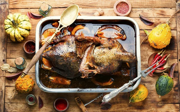 Eski ahşap masada balkabağı ve mantarla doldurulmuş kızarmış kaz.