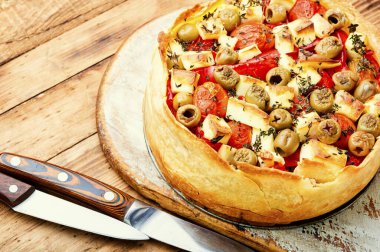 Kırsal ahşap masada peynirli, biberli ve zeytinli iştah açıcı tart