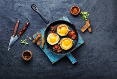 Fried eggs with tomatoes and bread in frying pan