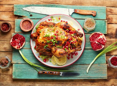 Tavuğun tamamı eski ahşap bir arka planda nar çileğiyle pişirilmiş..