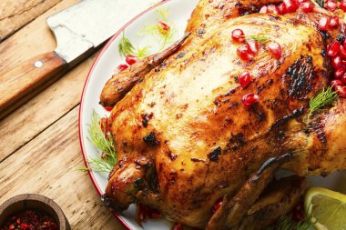 Tavuğun tamamı eski ahşap bir arka planda nar çileğiyle pişirilmiş..