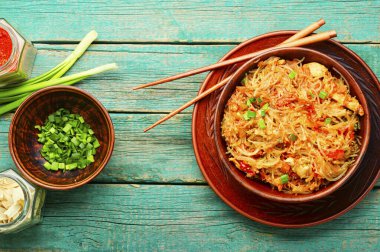 Funchoza, baharatlı Çin eriştesi ve ahşap masada tavuk eti.