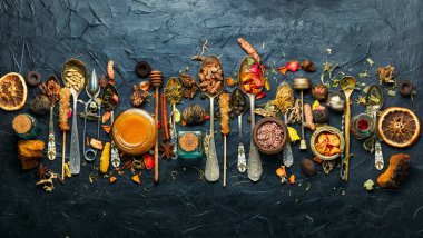 Kurutulmuş yeşil çay yaprakları ve çay kaşığında şifalı bitkiler.