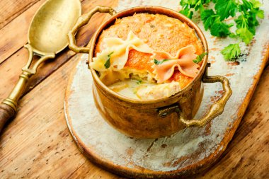 Tahta arka planda tavuk, peynir ve mantarlı makarna güveci