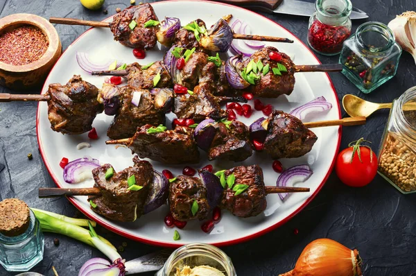 Grilled liver kebab with onion on wooden skewers