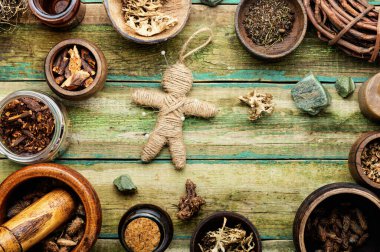 Voodoo bebeği, sihirli bitkiler ve eski bir masanın üzerindeki büyücülük özellikleri.